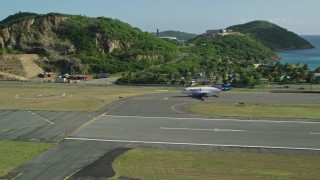 AX103_001 - 4.8K aerial stock footage of a jet at Cyril E King Airport along Caribbean blue waters, St Thomas