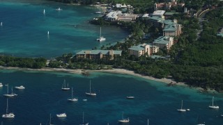 AX103_014E - 4.8K aerial stock footage fly over sailboats in Caribbean blue waters toward condos and resort, Muller Bay, St Thomas