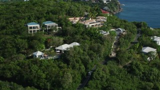 AX103_032E - 4.8K aerial stock footage of ocean view homes on a green hillside, Cruz Bay, St John