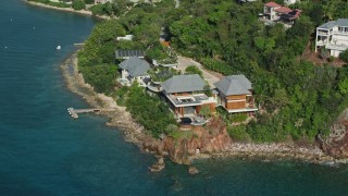 AX103_034 - 4.8K aerial stock footage of an Oceanfront mansion along turquoise blue Caribbean waters, Cruz Bay, St John