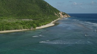 AX103_046 - 4.8K aerial stock footage of a Caribbean beach along jungle and sapphire blue Caribbean waters, Reef Bay, St John