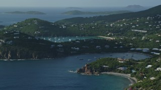 AX103_060E - 4.8K aerial stock footage of a hilltop and cliff top mansions near Caribbean blue waters, Cruz Bay, St John