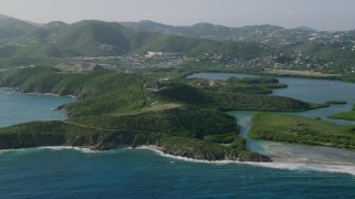 AX103_066 - 4.8K aerial stock footage of Tree covered cliffs near coastal town in Caribbean blue waters, East End, St Thomas