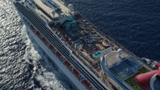 AX103_076E - 4.8K aerial stock footage of the pool area of carnival cruise ship in Caribbean blue waters,  St Thomas