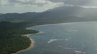 AX103_118 - 4.8K aerial stock footage of a Caribbean beach and jungle along turquoise blue waters, Fajardo, Puerto Rico