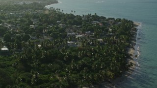 AX103_131E - 4.8K aerial stock footage of palm trees, beachfront homes and a resort by Caribbean blue waters, Loiza, Puerto Rico