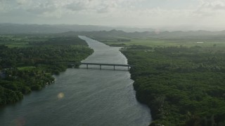 AX103_135E - 4.8K aerial stock footage of Caribbean beach and small bridge over a river, Loiza, Puerto Rico
