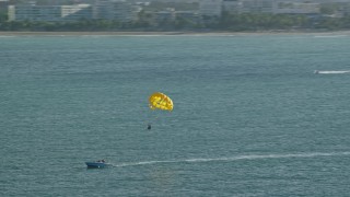 AX103_146 - 4.8K aerial stock footage Parasailing in Caribbean blue waters, San Juan, Puerto Rico