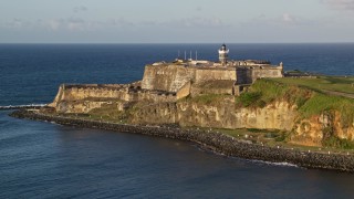 AX104_007E - 4.8K aerial stock footage of Fort San Felipe del Morro along Caribbean blue waters, Old San Juan, sunset