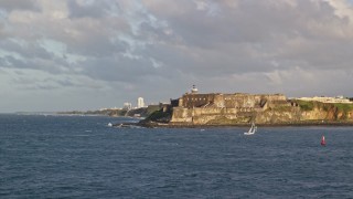 AX104_013 - 4.8K aerial stock footage of Fort San Felipe del Morro along Caribbean blue waters, Old San Juan, sunset