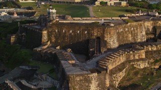 AX104_019E - 4.8K aerial stock footage of Fort San Felipe del Morro and lighthouse, Old San Juan, sunset