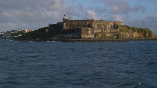 AX104_020 - 4.8K aerial stock footage of Fort San Felipe del Morro and lighthouse, Old San Juan, sunset