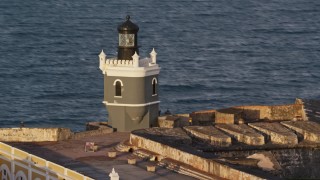 AX104_022 - 4.8K aerial stock footage of Port San Juan Light, Fort San Felipe del Morro, Old San Juan, sunset