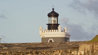 AX104_023E - 4.8K aerial stock footage of Port San Juan Light and Fort San Felipe del Morro, Old San Juan, sunset