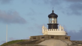 AX104_025 - 4.8K aerial stock footage of Port San Juan Light atop Fort San Felipe del Morro, Old San Juan, sunset
