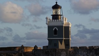 AX104_026E - 4.8K aerial stock footage of Port San Juan Light atop Fort San Felipe del Morro, Old San Juan, sunset