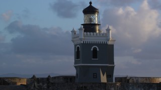AX104_027 - 4.8K aerial stock footage of Port San Juan Light atop Fort San Felipe del Morro, Old San Juan, sunset