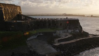 AX104_029 - 4.8K aerial stock footage of Fort San Felipe del Morro and blue ocean waters, Old San Juan, sunset