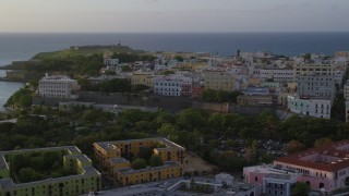 AX104_034 - 4.8K aerial stock footage of La Fortaleza among Caribbean buildings, Old San Juan, sunset