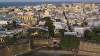 AX104_041 - 4.8K aerial stock footage of a Caribbean neighborhood, Old San Juan, Puerto Rico sunset