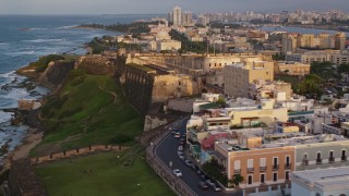 AX104_043E - 4.8K aerial stock footage Caribbean buildings and Fort San Cristobal, Old San Juan, Puerto Rico, sunset