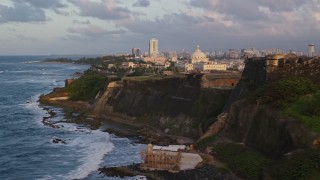 AX104_045 - 4.8K aerial stock footage of San Juan Capitol Building along the ocean, Old San Juan Puerto Rico, sunset
