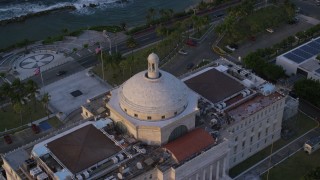 AX104_048 - 4.8K aerial stock footage of San Juan Capitol Building looking out on the ocean, Old San Juan Puerto Rico, sunset