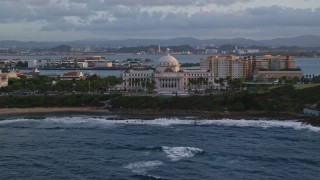 AX104_050 - 4.8K aerial stock footage of San Juan Capitol Building along the coast, Old San Juan, Puerto Rico, sunset