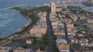AX104_053 - 4.8K aerial stock footage Following Avenida Juan Ponce de Leon through buildings, Old San Juan, Puerto Rico, sunset