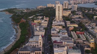 AX104_053E - 4.8K aerial stock footage following Avenida Juan Ponce de Leon past buildings, Old San Juan, Puerto Rico, sunset