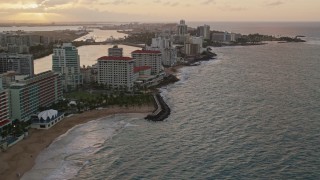 AX104_069E - 4.8K aerial stock footage of beachfront Caribbean hotels along the ocean, San Juan, Puerto Rico, sunset
