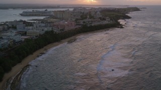 AX104_076 - 4.8K aerial stock footage Approaching San Juan Capitol Building along the coast, Puerto Rico, sunset