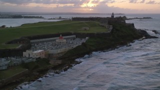AX104_080 - 4.8K aerial stock footage Approaching Fort San Felipe del Morro and lighthouse, Old San Juan, sunset