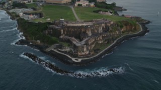 AX104_084 - 4.8K aerial stock footage of Fort San Felipe del Morro along Caribbean blue waters, Old San Juan, twilight
