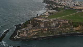 AX104_086E - 4.8K aerial stock footage of Fort San Felipe del Morro and Caribbean blue ocean waters, Old San Juan, twilight