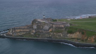 AX104_088 - 4.8K aerial stock footage of Fort San Felipe del Morro along Caribbean blue ocean waters, Old San Juan, twilight