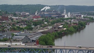 AX105_044E - 4.8K aerial stock footage ascend over bridge and reveal a U.S. Steel Mon Valley Works, Braddock, Pennsylvania