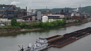 AX105_053E - 4.8K aerial stock footage of River Barge near U.S. Steel Mon Valley Works, Braddock, Pennsylvania