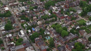 AX105_206E - 4.8K aerial stock footage flying over town houses and row houses and reveal school, Pittsburgh, Pennsylvania