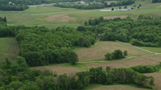 AX106_050E - 4.8K aerial stock footage of barns, trees, and green fields in Koppel, Pennsylvania