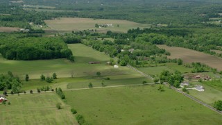 AX106_143 - 4.8K aerial stock footage of farmland and red barns in Windham, Ohio