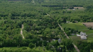 AX106_144 - 4.8K aerial stock footage of a country road by farms in Garrettsville, Ohio