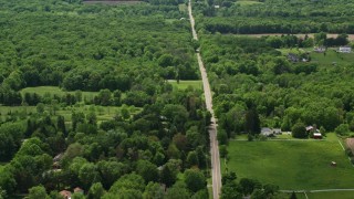 AX106_144E - 4.8K aerial stock footage of a country road by farms in Garrettsville, Ohio