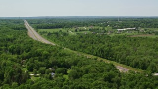 AX106_166 - 4.8K aerial stock footage orbiting a highway by forest in Chagrin Falls, Ohio