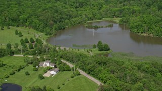 AX107_076E - 4.8K aerial stock footage of isolated lakeside home surrounded by trees, Aurora, Ohio