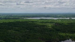 AX107_092E - 4.8K aerial stock footage flying over forest toward a reservoir, Ravenna, Ohio
