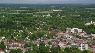 AX107_100E - 4.8K aerial stock footage flying over small town and greenhouses toward a school, Columbiana, Ohio