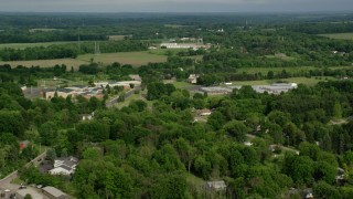 AX107_102 - 4.8K aerial stock footage flying over trees and greenhouses toward a middle school, Columbiana, Ohio