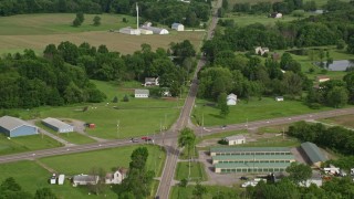 AX107_105E - 4.8K aerial stock footage following a country road past barns and farmland, Columbiana, Ohio