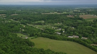 AX107_111E - 4.8K aerial stock footage flying over forests toward rural homes, East Palestine, Ohio